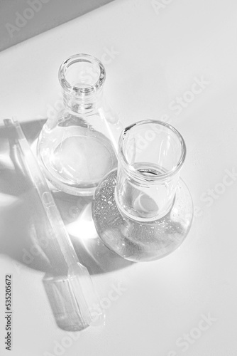 Transparent glass flask on a white background. science research chemistry banner laboratory background. Serum with a pipette in the laboratory. Cosmetic research.