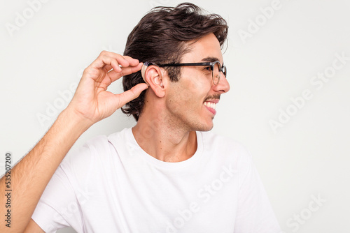 Young hispanic man wearing hearing aid isolated on white background
