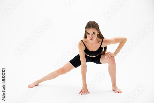 Beautiful brunette fitness woman doing yoga on a white background
