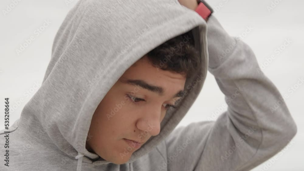 Closeup portrait of hispanic teenager runner boy removing the hood of sweatshirt and looking around. Closeup portrait of hispanic teenager runner boy removing the hood of sweatshirt and looking around.