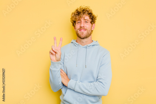 Young caucasian man isolated on yellow background showing number two with fingers.