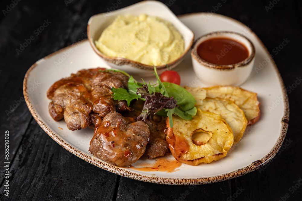 grilled meat with vegetables and spices on a black background
