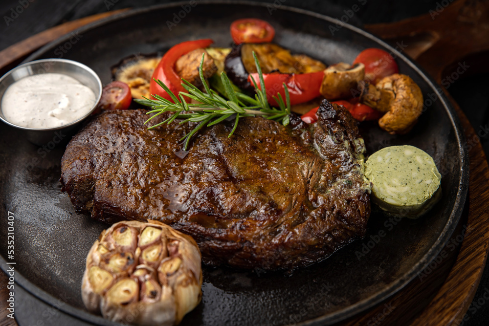 grilled meat with vegetables and spices on a black background
