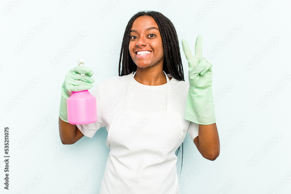 Young African American cleaner woman isolated on blue background showing number two with fingers. Young African American cleaner woman isolated on blue background showing number two with fingers.