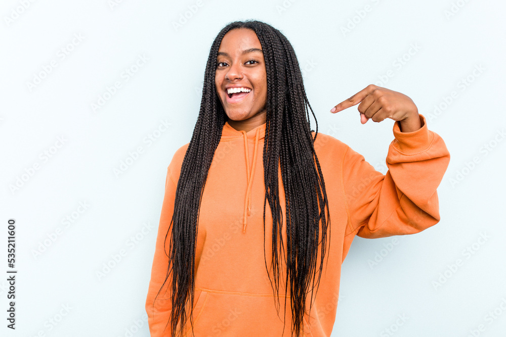 Young African American woman with braids hair isolated on blue background person pointing by hand to a shirt copy space, proud and confident Young African American woman with braids hair isolated on blue background person pointing by hand to a shirt copy space, proud and confident