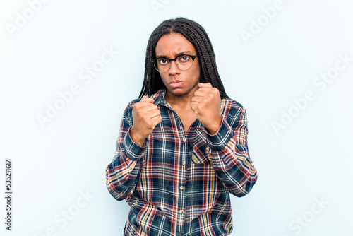 Young African American woman with braids hair isolated on blue background showing fist to camera, aggressive facial expression.