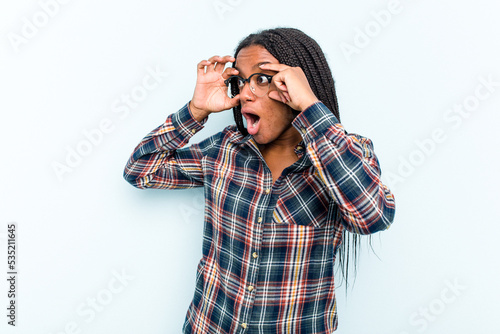Young African American woman with braids hair isolated on blue background keeping eyes opened to find a success opportunity.