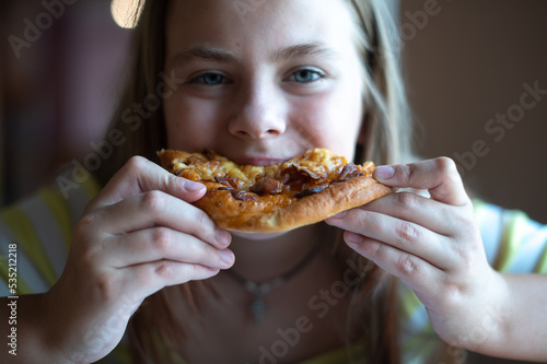 Cute teenage girl eating pizza  close-up of face with blue eyes