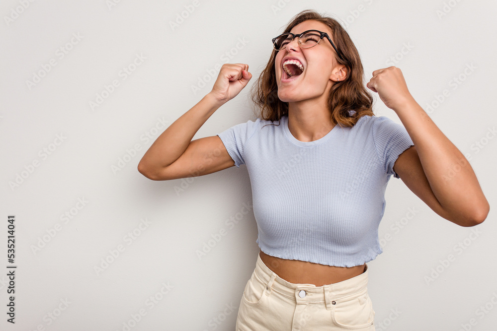 Young caucasian woman isolated on blue background raising fist after a victory, winner concept. Young caucasian woman isolated on blue background raising fist after a victory, winner concept.