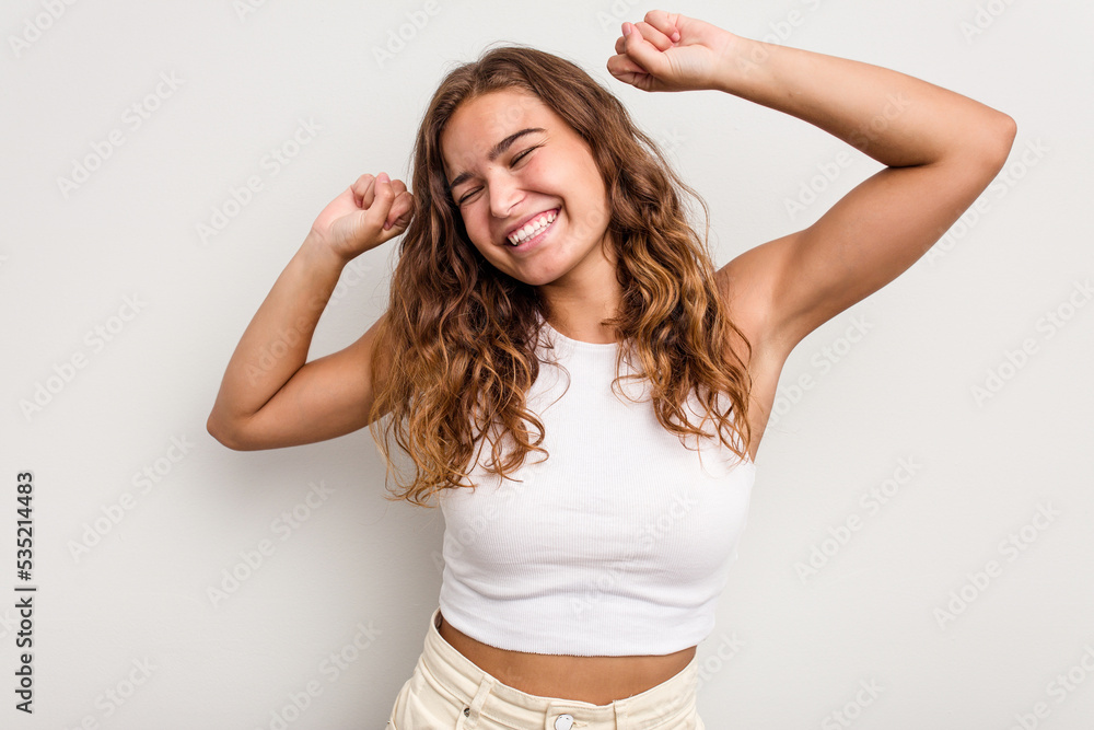 Young caucasian woman isolated on blue background celebrating a special day, jumps and raise arms with energy. Young caucasian woman isolated on blue background celebrating a special day, jumps and raise arms with energy.