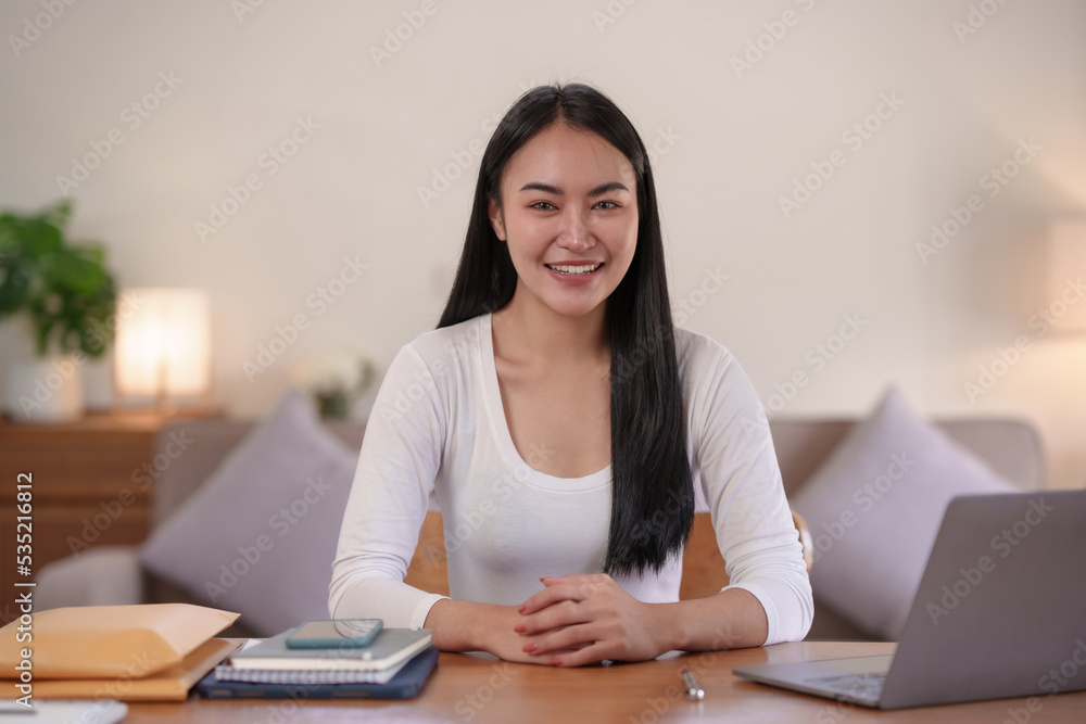 Beautiful Asian woman sitting intently working on a laptop computer at home. Beautiful Asian woman sitting intently working on a laptop computer at home.