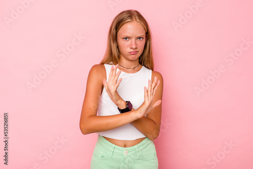 Caucasian teen girl isolated on pink background doing a denial gesture