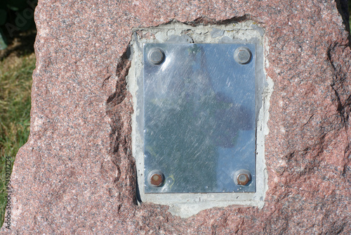 metal plate on granite stone in park at dry sunny summer day