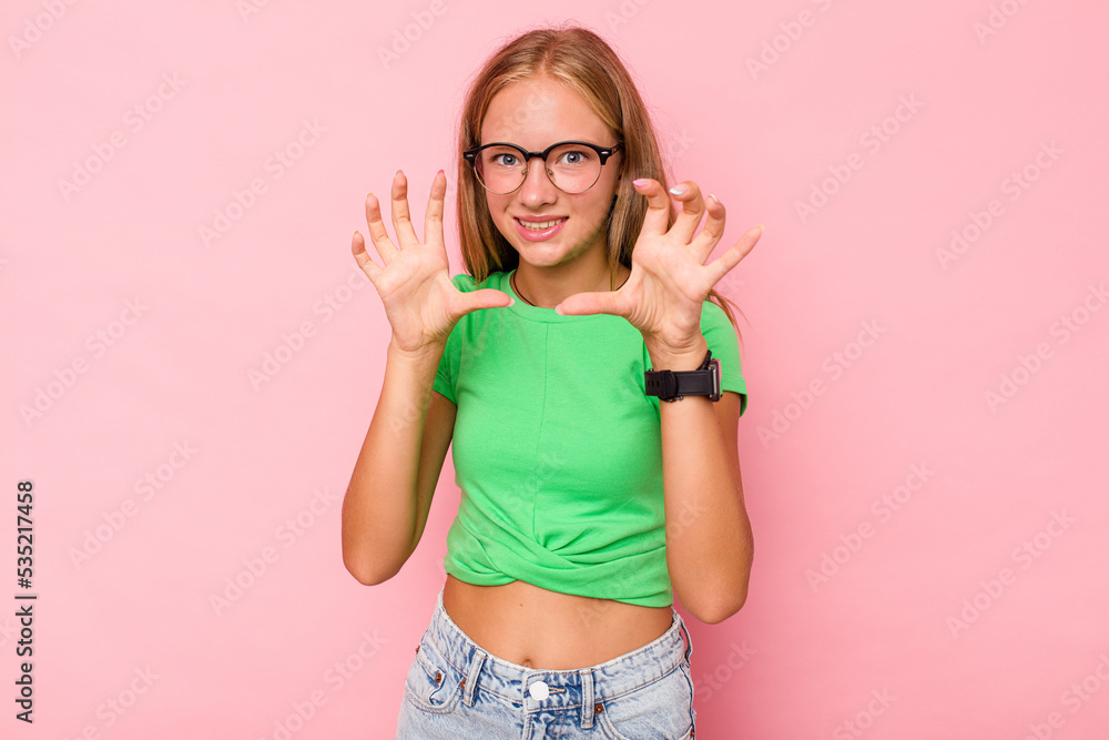 Caucasian teen girl isolated on pink background showing claws imitating a cat, aggressive gesture. Caucasian teen girl isolated on pink background showing claws imitating a cat, aggressive gesture.