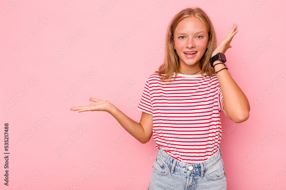 Caucasian teen girl isolated on pink background holds copy space on a palm, keep hand over cheek. Amazed and delighted. Caucasian teen girl isolated on pink background holds copy space on a palm, keep hand over cheek. Amazed and delighted.
