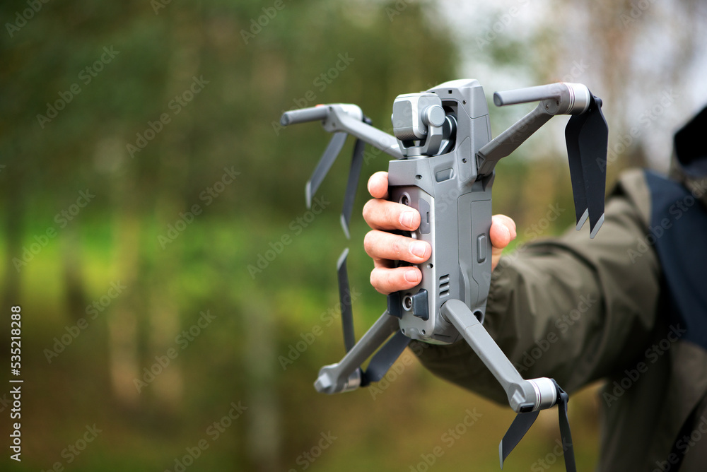 Man holding a drone with his hand before flying it through the sky Man holding a drone with his hand before flying it through the sky