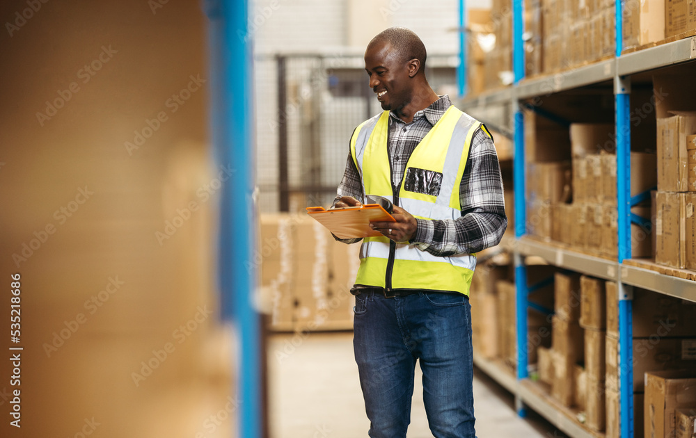 Happy warehouse manager taking stock using a barcode scanner in a logistics centre Happy warehouse manager taking stock using a barcode scanner in a logistics centre
