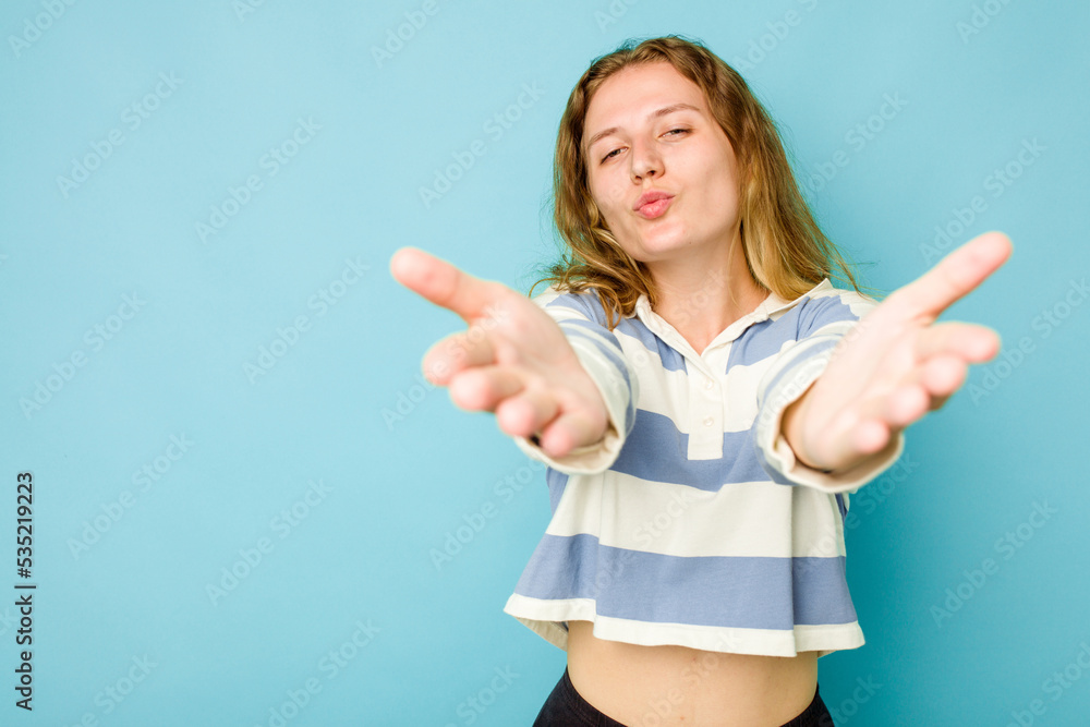 Young caucasian woman isolated on blue background folding lips and holding palms to send air kiss. Young caucasian woman isolated on blue background folding lips and holding palms to send air kiss.