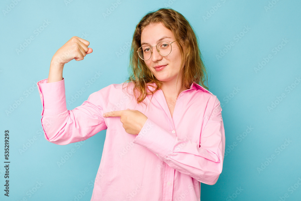 Young caucasian woman isolated on blue background showing strength gesture with arms, symbol of feminine power Young caucasian woman isolated on blue background showing strength gesture with arms, symbol of feminine power