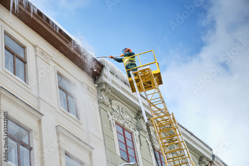 Public utilities on special vehicles remove icicles from the roofs of houses on the Rynok square in Lviv. Roof Winter Workers.