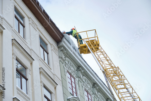 Public utilities on special vehicles remove icicles from the roofs of houses on the Rynok square in Lviv. Roof Winter Workers.
