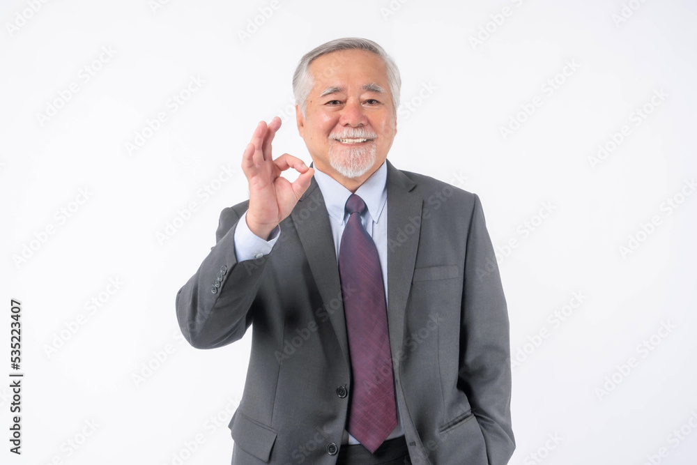 Asian senior businessman , old man with suit and tie showing ok gesture hand standing and looking at camera isolated on white background with copy space - lifestyle senior male concept Asian senior businessman , old man with suit and tie showing ok gesture hand standing and looking at camera isolated on white background with copy space - lifestyle senior male concept