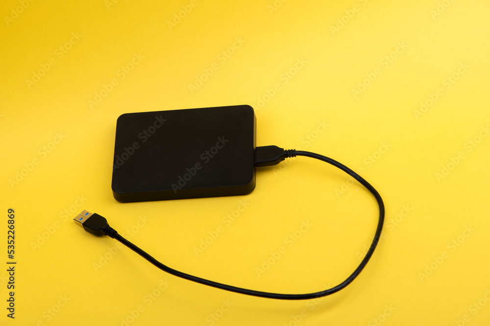 Black external portable hard disk drives isolated on yellow background Black external portable hard disk drives isolated on yellow background