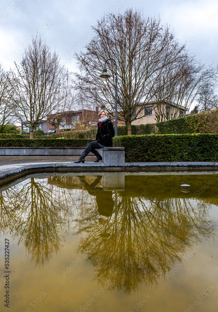 Obraz premium Model posing at a water pond with her profile reflecting in the water