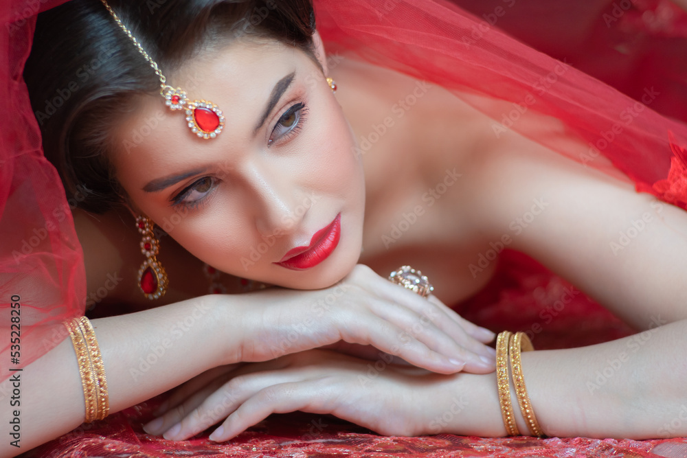 Beautiful portrait pretty woman red dressed as an Indian sexy girl with red  lips. Young Hindu Pakistani Bride and glamour makeup in a fashion jewelry  set. Stock Photo | Adobe Stock