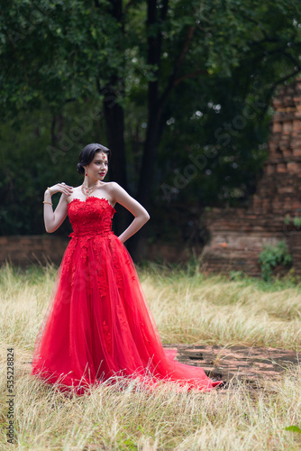 Beautiful portrait pretty woman red dressed as an Indian sexy girl with red lips. Young Hindu Pakistani Bride and glamour makeup in a fashion jewelry set.