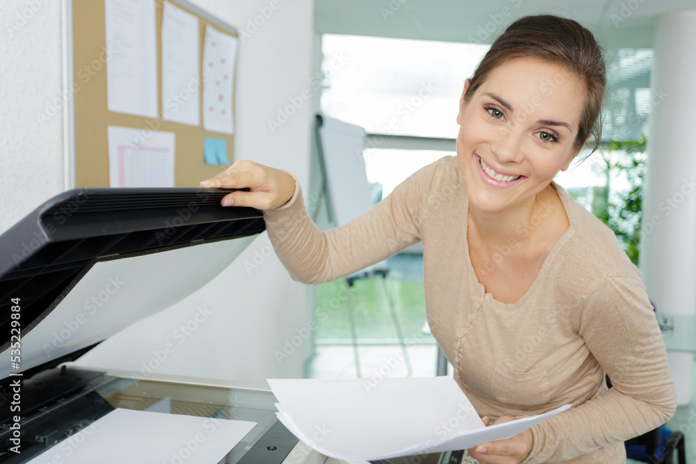 happy businesswoman standing by photocopier happy businesswoman standing by photocopier