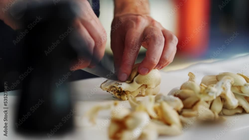 close-up of a chef cutting a porcini mushroom a board in a loft-style kitchen close-up of a chef cutting a porcini mushroom a board in a loft-style kitchen