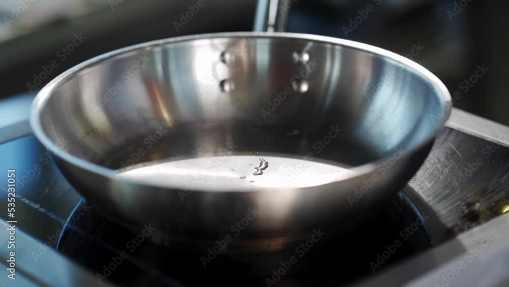chef splashing oil on metal pan in loft style kitchen chef splashing oil on metal pan in loft style kitchen
