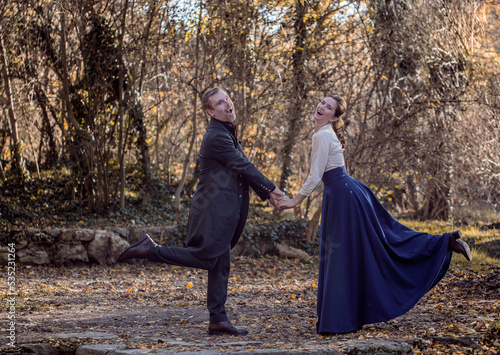 Vampire man wearing victorian suit with vampire woman in the autumn forest. Vintage medieval concept style.