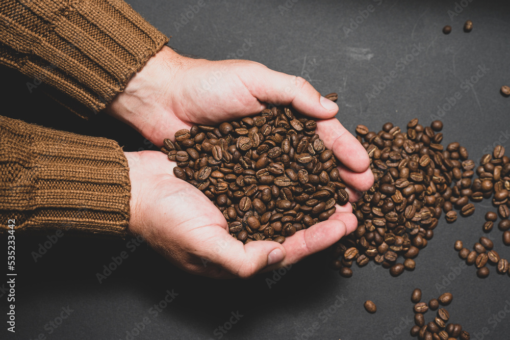 Fototapeta premium Male hands hold coffee on a dark background.