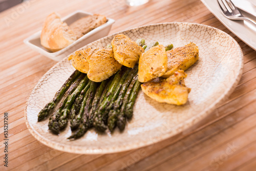 fried chicken breast pieces with asparagus on white plate