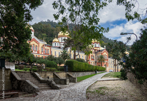 New Athos, Abkhazia - October 20, 2021. The New Athos Monastery with bright golden domes on a sunny autumn day among green trees .