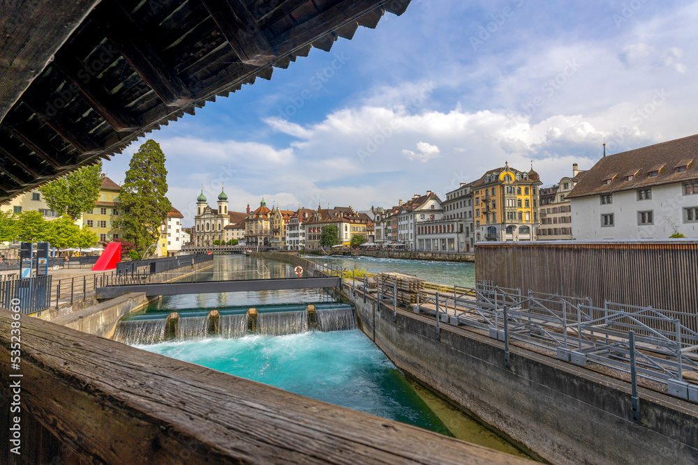 LUCERNE, SWITZERLAND, JUNE 21, 2022 - Small waterfalls of Reuss river with historic buildings on the background in the center city of Lucerne, Switzerland