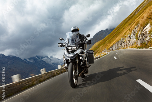 Quadro su tela Motorbiker riding in Austrian Alps, dramatic sky