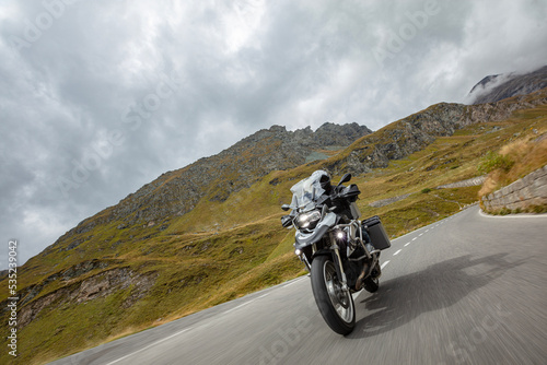 Motorbiker riding in Austrian Alps  dramatic sky. Travel and freedom  outdoor activities