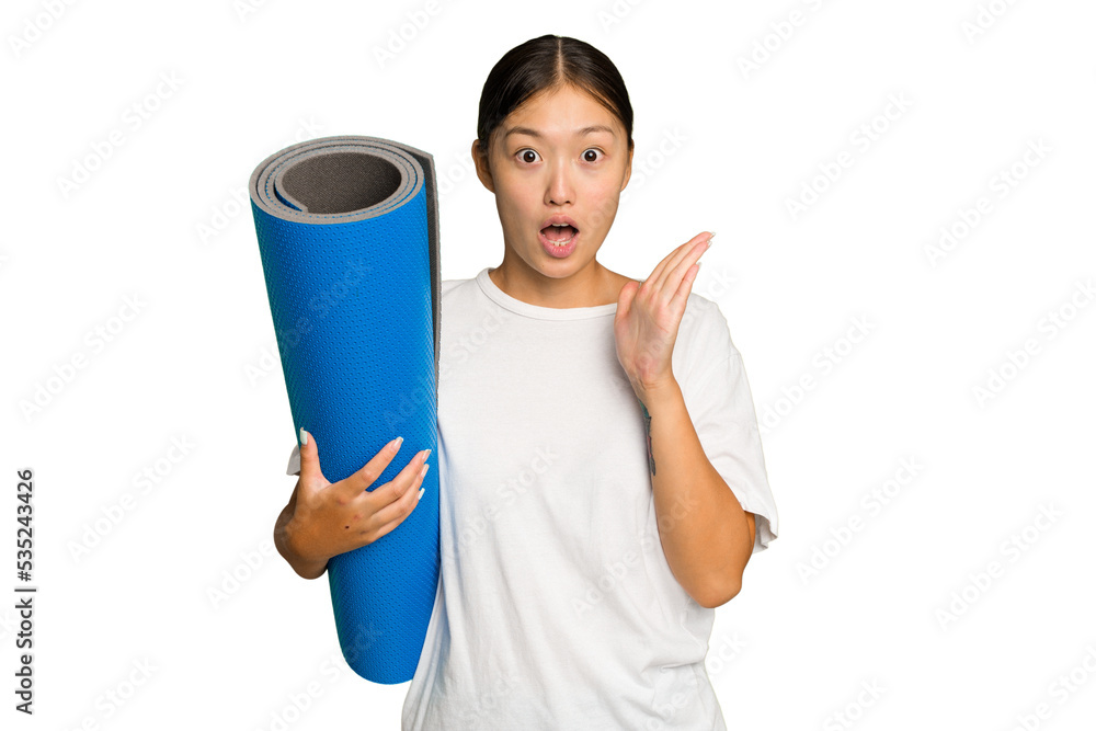 Young asian woman holding a mat isolated on green chroma background surprised and shocked. Young asian woman holding a mat isolated on green chroma background surprised and shocked.