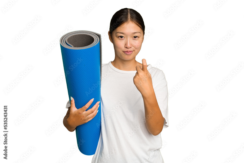 Young asian woman holding a mat isolated on green chroma background pointing with finger at you as if inviting come closer. Young asian woman holding a mat isolated on green chroma background pointing with finger at you as if inviting come closer.