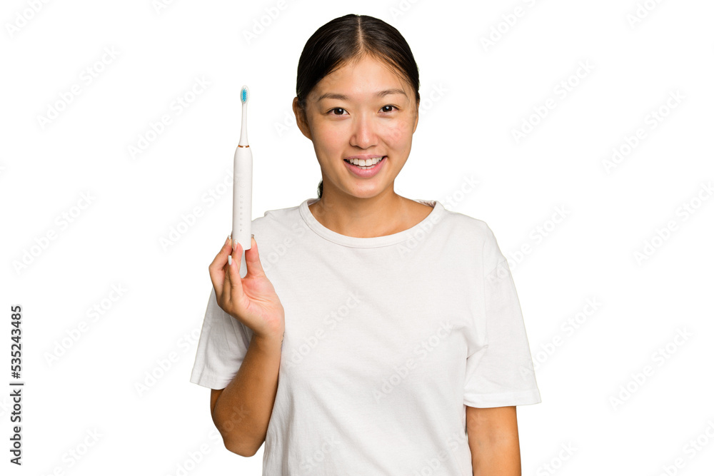 Young Asian woman holding an electric toothbrush isolated on green chroma background happy, smiling and cheerful. Young Asian woman holding an electric toothbrush isolated on green chroma background happy, smiling and cheerful.
