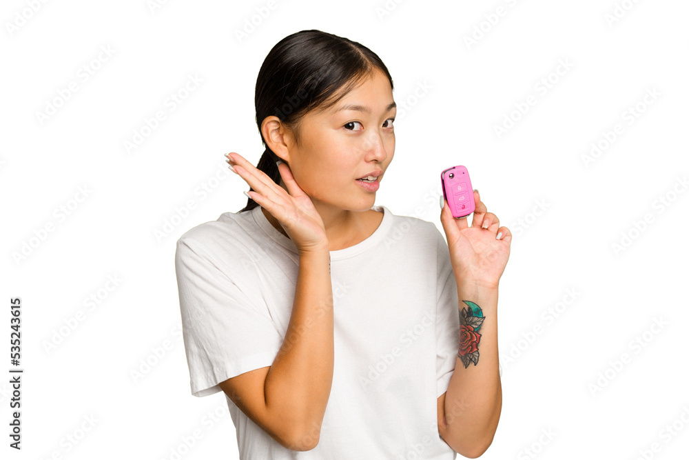 Young asian woman holding car keys isolated on green chroma background trying to listening a gossip. Young asian woman holding car keys isolated on green chroma background trying to listening a gossip.
