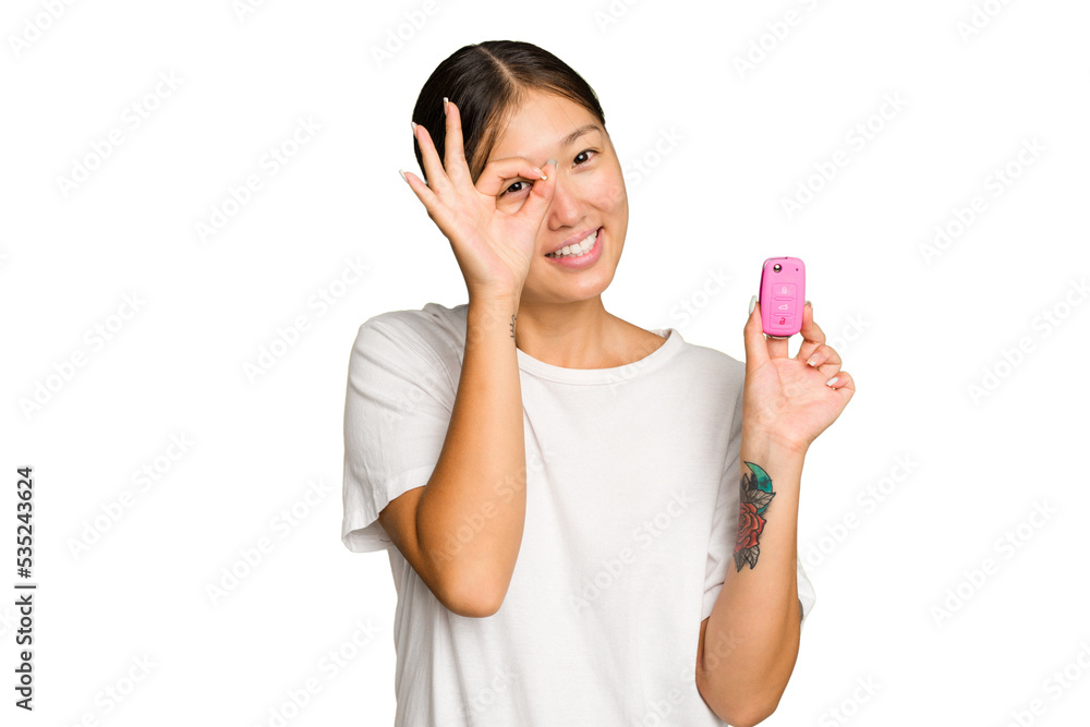 Young asian woman holding car keys isolated on green chroma background excited keeping ok gesture on eye. Young asian woman holding car keys isolated on green chroma background excited keeping ok gesture on eye.
