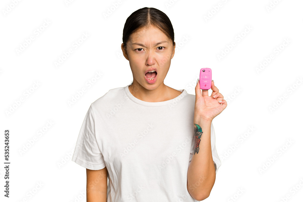 Young asian woman holding car keys isolated on green chroma background screaming very angry and aggressive. Young asian woman holding car keys isolated on green chroma background screaming very angry and aggressive.