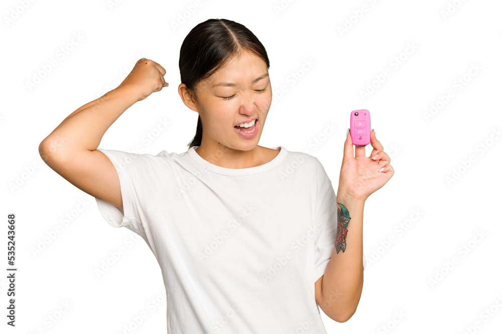 Young asian woman holding car keys isolated on green chroma background raising fist after a victory, winner concept. Young asian woman holding car keys isolated on green chroma background raising fist after a victory, winner concept.