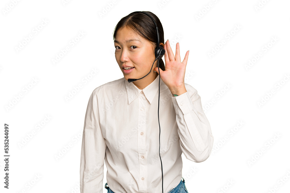 Telemarketer asian woman working with a headset isolated on green chroma background trying to listening a gossip. Telemarketer asian woman working with a headset isolated on green chroma background trying to listening a gossip.