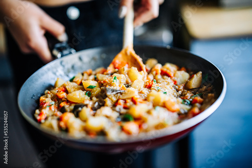 Woman cooking tasty vegetable stew in pan on kitchen