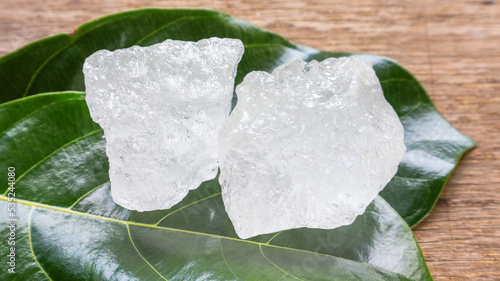 Crystal clear alum cubes or Potassium alum on green leaf. Chemical compound substance. Concept for beauty, spa and underarm treatment industrial.                                                       photo